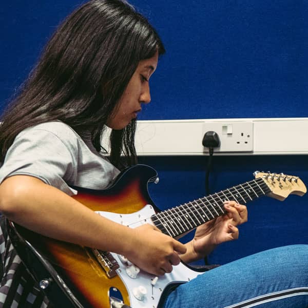 Child learning electric guitar in Wrexham